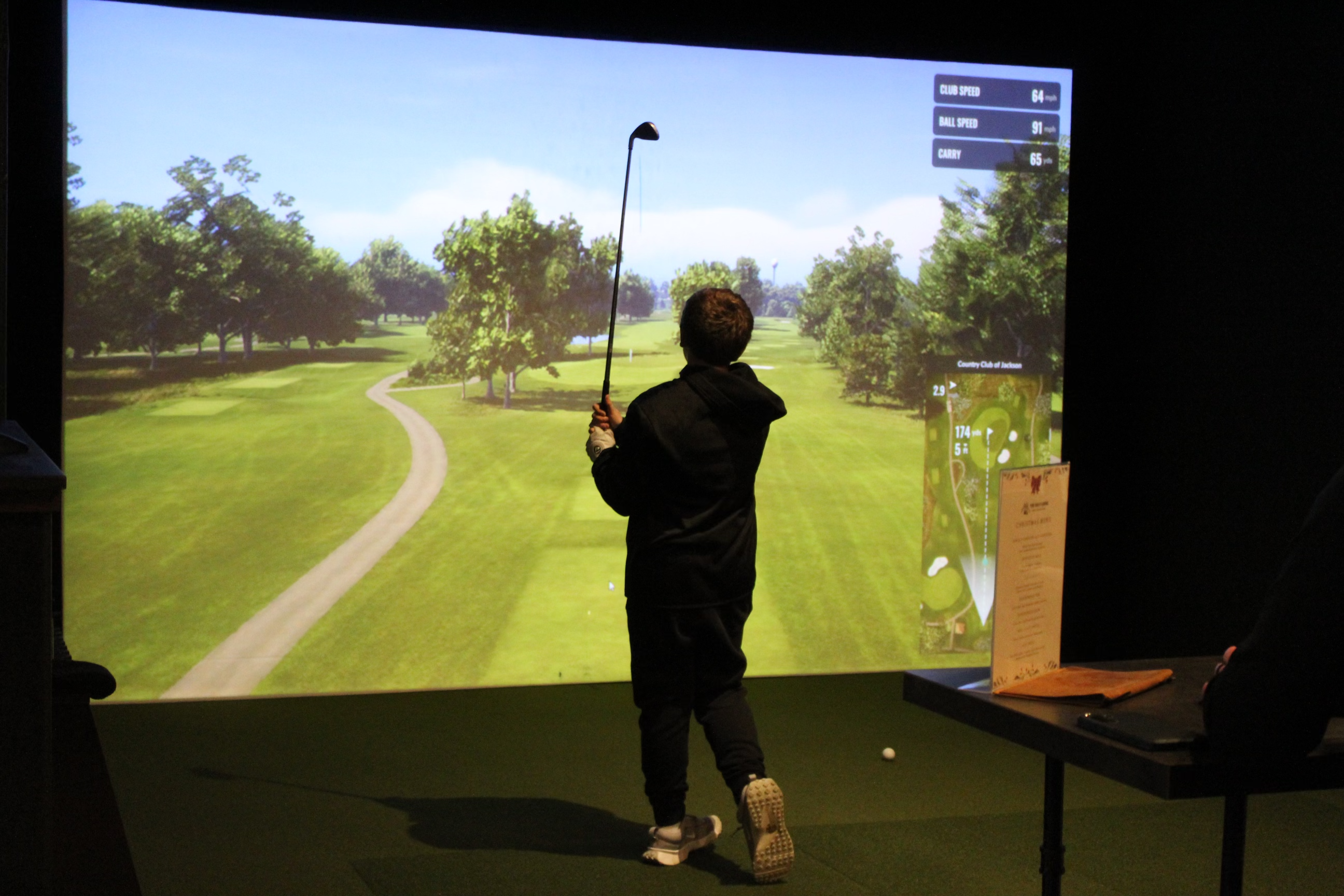 Golfer mid-swing on the Trackman simulator